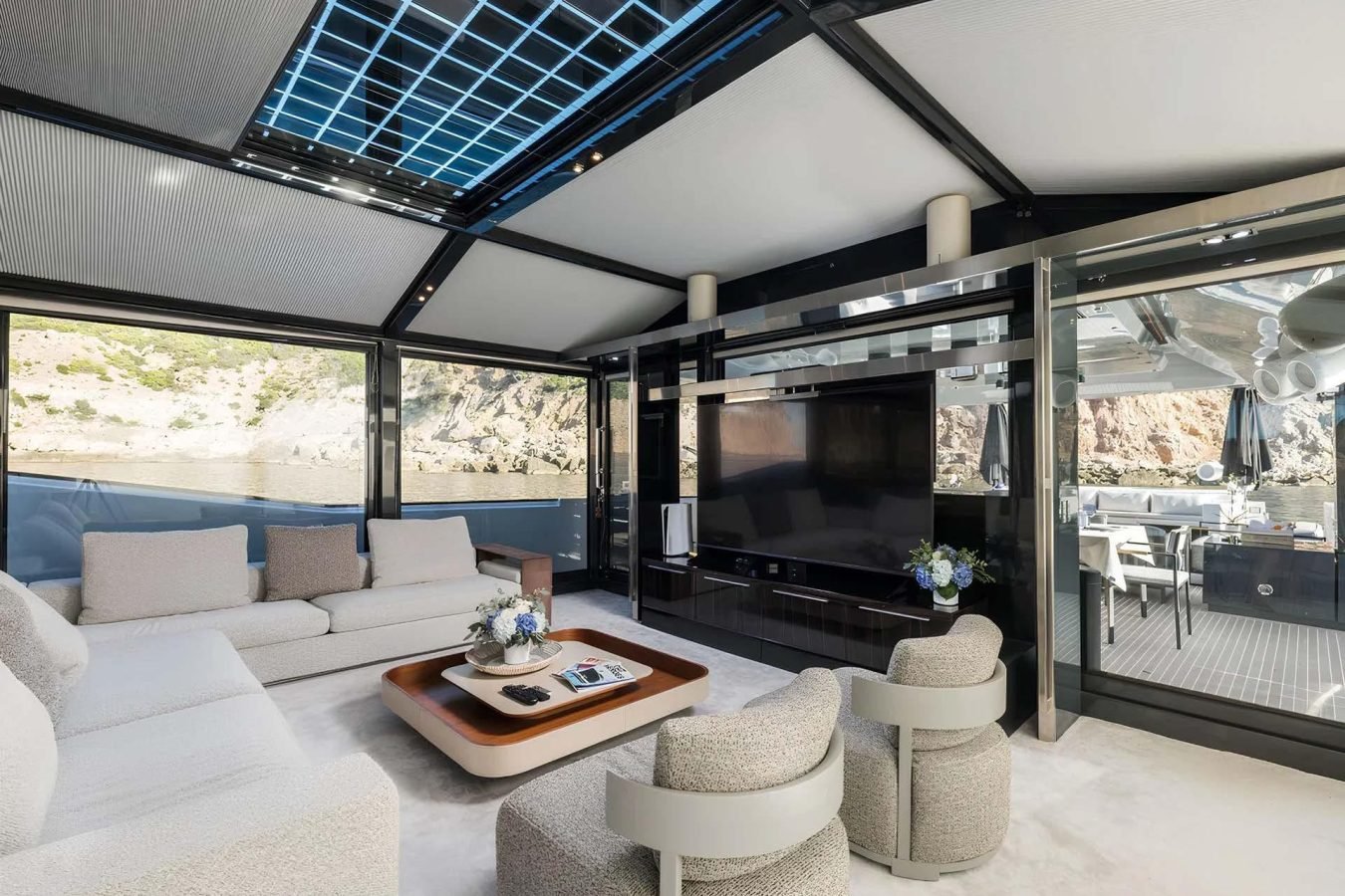 Modern yacht lounge on Arcadia 85 with plush seating, large TV, glass walls, and sweeping views—perfect yacht for charter.
