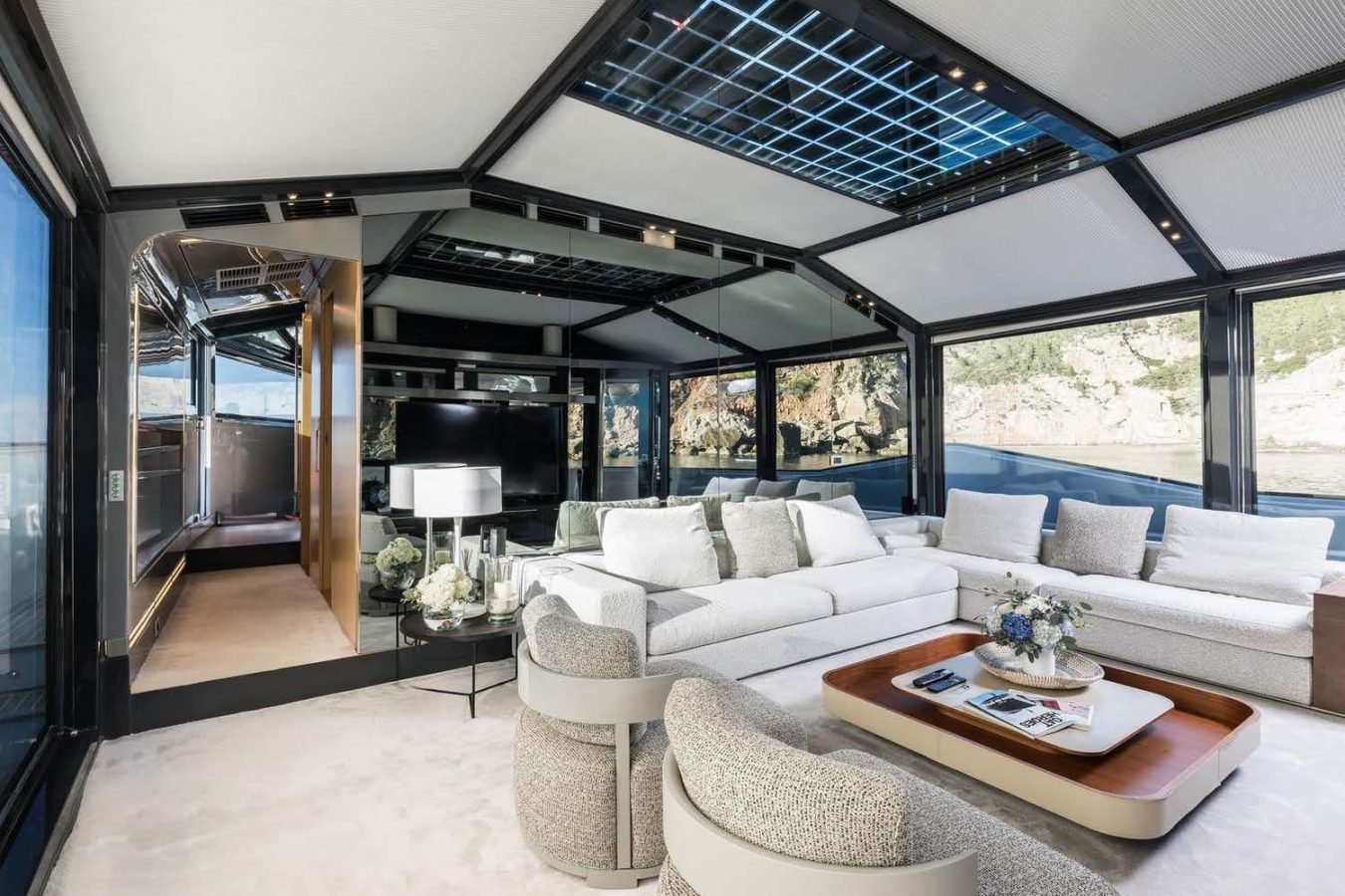 Modern yacht lounge aboard Arcadia 85 with large windows, white sofas, armchairs—perfect for a yacht for charter.