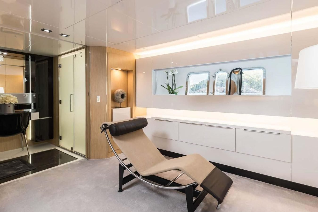Modern room reminiscent of the elegant Arcadia 85 yacht for charter, with tan chaise, cabinets, and orchid accents.
