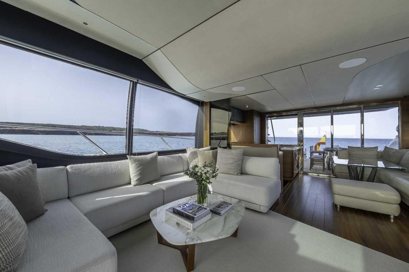 Modern yacht interior with white sofas, marble table, and ocean views aboard the luxurious Princess S78 Yacht for Charter.