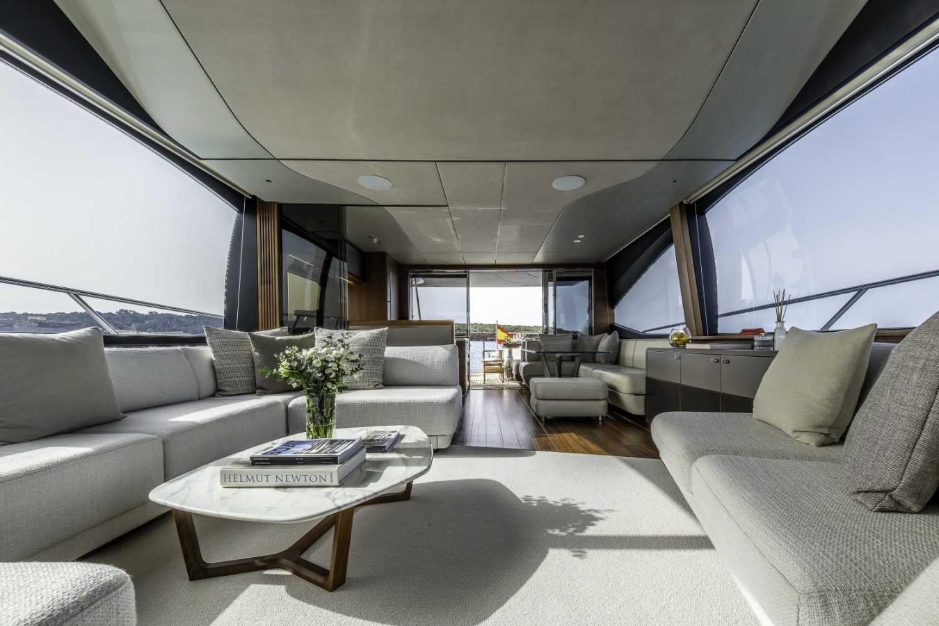 Modern yacht interior on the Princess S78 with large windows, white sofas, and views into Why Knot Yacht’s dining area.