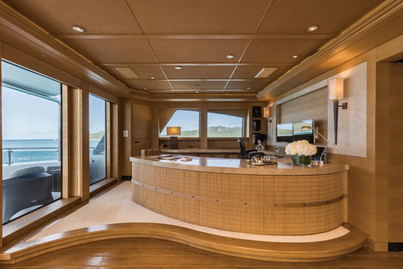 Luxurious Freire Naia Yacht for Charter interior with wood paneling, large windows, ocean view, and elegant decor.